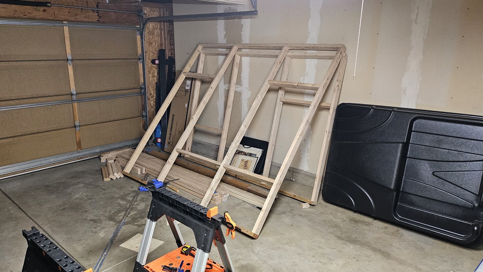 Two angled wall frames standing finished in the garage.