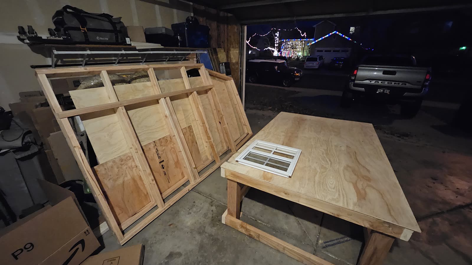 Sheathed wall panels leaning in the garage, one with its vent already fitted.